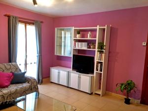 sala de estar con paredes de color rosa y TV de pantalla plana. en Apartamentos Tuara, en El Run