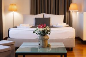 a hotel room with a bed and a vase with flowers on a table at Hotel Creina in Kranj +40 photos