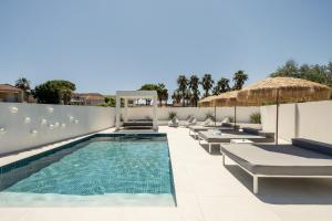 a swimming pool with chaise lounges and umbrellas at Moon Boutique Hotel - Ultra Luxury Suites with Pool, Perfect for Fun and Relaxation By Villa Mana Gers in Laganas