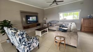 a living room with a couch and chairs and a tv at Eight Umdoni North in Pennington
