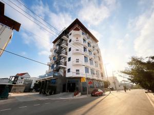 a tall white building with a red car parked next to it at Mimosa 8 Hotel - Ninh Chử in Ninh Hải