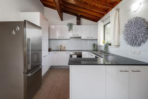 a kitchen with white cabinets and a stainless steel refrigerator at Drifters @ Callala Beach in Callala Beach