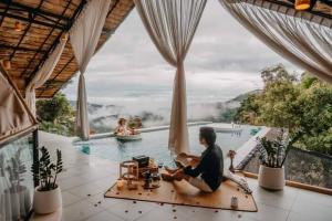 a woman sitting on the floor in front of a swimming pool at เดอะเฌอร์ โฮมสเตย์-The Sher in Ban Thung Phan Ha