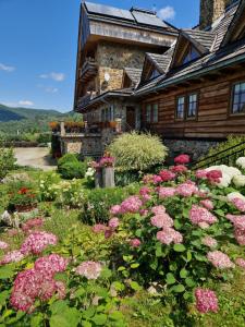 a garden with pink flowers in front of a house at Pokoje Gościnne u Laskowskich in Smerek