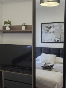 a mirror in a bedroom with a bed and a television at Aura Apartmani Vrnjačka Banja in Vrnjci