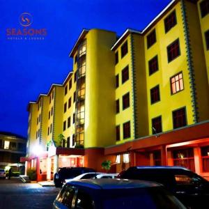 a yellow building with cars parked in a parking lot at Seasons Airport Hotel Nairobi in Nairobi
