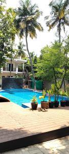 a swimming pool with potted plants in front of a house at Moonlight Resorts Idappadi in Ammāpettai