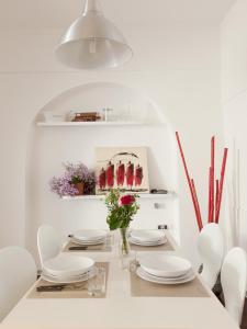 a white dining room with white plates and flowers on a table at Trastevere Art House in Rome