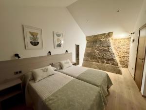 a bedroom with two beds and a stone wall at Mar Do Val in Muxia