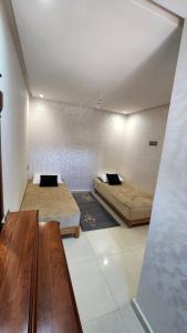 a room with two beds and a table in it at Sidi Rahal in Sidi Rahal