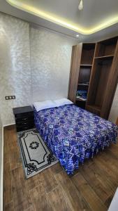 a bedroom with a bed with a blue comforter at Sidi Rahal in Sidi Rahal