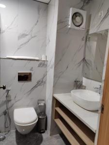 a white bathroom with a sink and a toilet at FlxHo Corporate Stays - Udyog Vihar in Gurgaon +12 photos