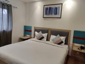 a bedroom with a large white bed with pillows at FlxHo Corporate Stays - Udyog Vihar in Gurgaon