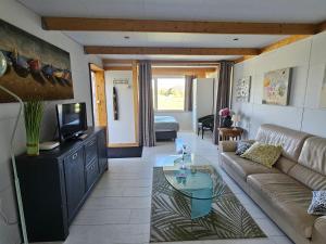 a living room with a couch and a tv at Little Creek - Lodges in het natuurgebied in Renesse