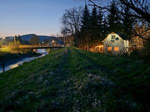 a house on the side of a river with a bridge at Holiday House Lawendowa Przystań - dom z jacuzzi nad jeziorem in Miszkowice