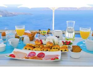 a table with breakfast foods and drinks on a table at Kafieris Blue in Firostefani
