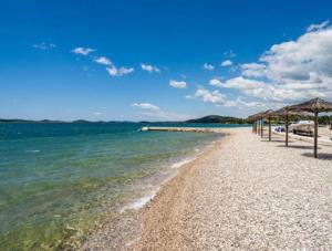 a sandy beach with umbrellas and the ocean at Adria Mobile Home in Pirovac