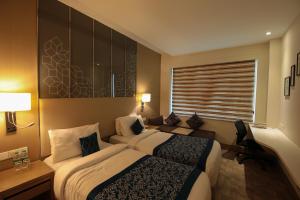 a hotel room with two beds and a couch at Days Hotel Jaipur Tonk Road By Wyndham in Jaipur +60 photos