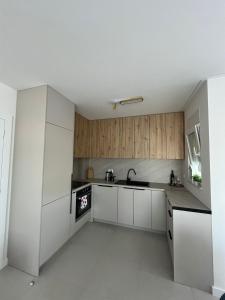 a white kitchen with wooden cabinets and a sink at Ana in Posušje +8 photos
