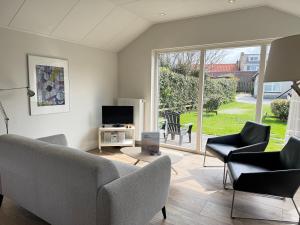 a living room with a couch and chairs and a tv at Op 't Landtweg 35a in Callantsoog