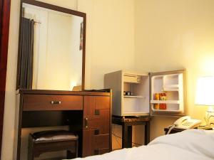 a bedroom with a dresser with a mirror and a refrigerator at St Augustine Apart & Hotel in Kigali