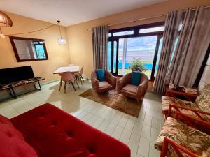 a living room with a red couch and chairs at Casa de temporada enfrente a praia in Itanhaém