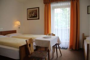 a room with two beds and a table and a window at Garni Villa Linda in Corvara in Badia