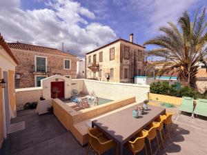 a patio with a table and chairs and a building at The Bellhouse Kranidi in Kranidi