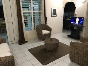 d'un salon avec des chaises en osier et une télévision. dans l'établissement Maison de Vacances à St Anne Martinique, à Sainte-Anne