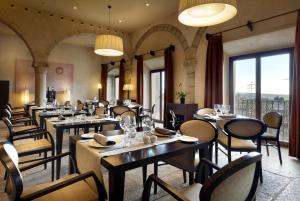 a restaurant with tables and chairs and windows at Eurostars Palacio de Santa Marta in Trujillo