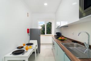 a kitchen with a sink and a refrigerator at Garden Apartment with BBQ & Orange Tree - Near Lisbon & Sintra in Queluz
