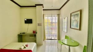 a room with a couch and a table and a window at RedDoorz @ Greenview Hotel and Restobar Masbate in Masbate +44 photos