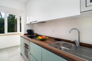 a kitchen with a sink and a bowl of fruit on the counter at Garden Apartment with BBQ & Orange Tree - Near Lisbon & Sintra in Queluz +15 photos