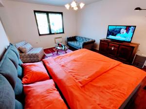 a living room with an orange bed and a flat screen tv at Apartment Green Garden in Sarajevo