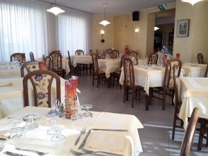 een eetkamer met tafels en stoelen met witte tafelkleden bij Hotel Mignon in Ponte di Legno