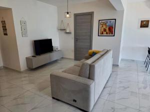 a living room with a couch and a television at Coastline, Lovely Seafront Apartment in Birżebbuġa