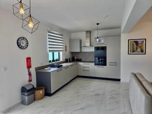 a kitchen with white cabinets and a clock on the wall at Coastline, Lovely Seafront Apartment in Birżebbuġa