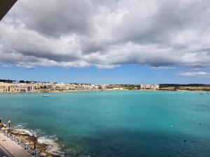 a large body of water with a city in the background at Coastline, Lovely Seafront Apartment in Birżebbuġa