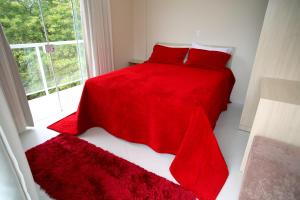 a bedroom with a red bed with red pillows and a window at Pousada Magnus in Balneário Camboriú