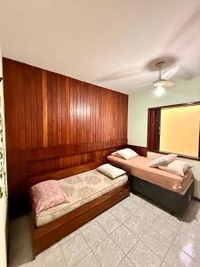 two beds in a room with wooden walls at Casa de temporada enfrente a praia in Itanhaém