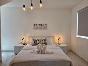 two towels on a bed in a bedroom with lights at Coastline, Lovely Seafront Apartment in Birżebbuġa