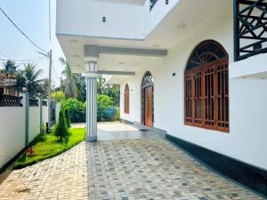 a white house with a door and a walkway at Vish Homes in Nallur