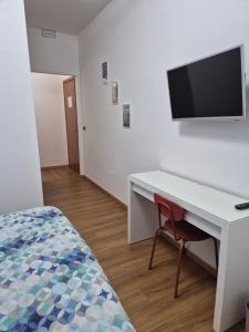 a bedroom with a desk and a tv on a wall at Il Giramondo in Aversa