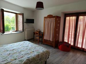 a bedroom with a bed and a desk and windows at Chez Bonjour in Villar Pellice