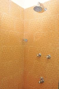 a shower in a bathroom with an orange tile wall at Villa Theresa Beach Resort in Calangute