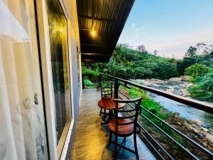 a balcony with two chairs and a view of a river at Edinburgh Cottage's in Nanu Oya
