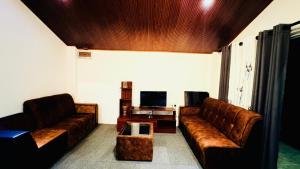 a living room with leather couches and a tv at Edinburgh Cottage's in Nanu Oya