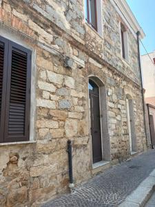 a stone building with a door and windows on a street at La Gradinata in Gonnosfanàdiga