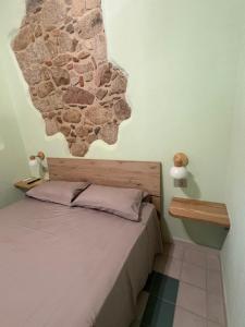 a bedroom with a bed with a stone wall at La Gradinata in Gonnosfanàdiga +5 photos