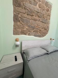 a bedroom with a bed with a brick wall at La Gradinata in Gonnosfanàdiga